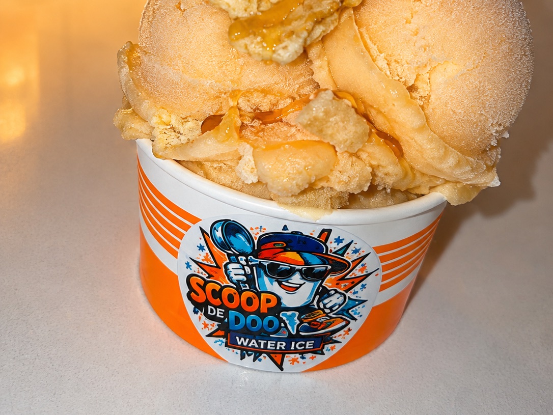 A large cup of peach water ice loaded with cookie crumble and caramel drizzle